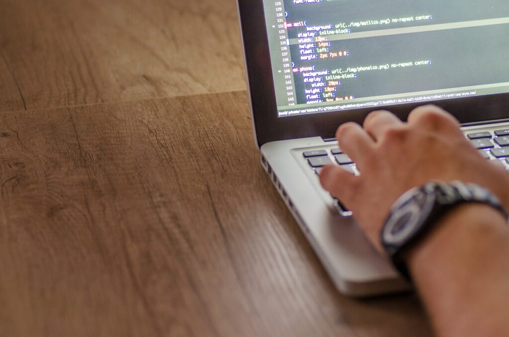 Een hand met een horloge om typt code in de terminal op een laptop.